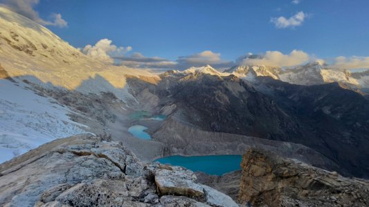 Turquoise glacial lakes nestled in a rugged valley at golden hour, viewed from a rocky summit