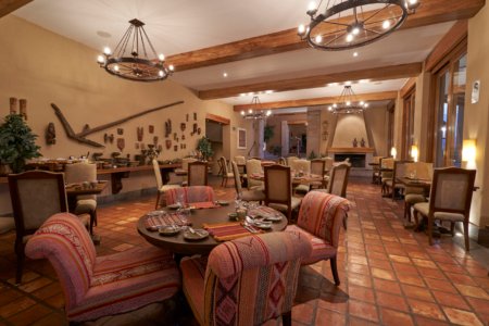 Andean lodge restaurant with wrought-iron chandeliers, fireplace and textile-upholstered chairs