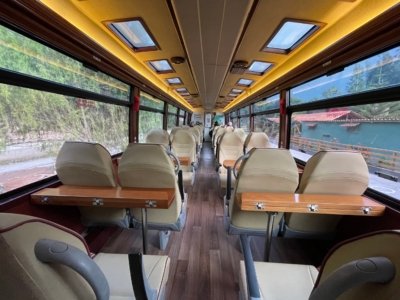 Empty panoramic tourist bus interior with cream leather seats and folding wood trays