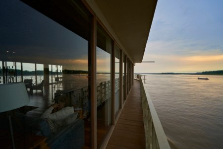 Riverboat balcony walkway overlooking the Amazon at sunset with a guest lounging inside