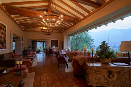 Grand hacienda living room with timber-beam ceiling, iron chandeliers and mountain views, by Alexander Estrada
