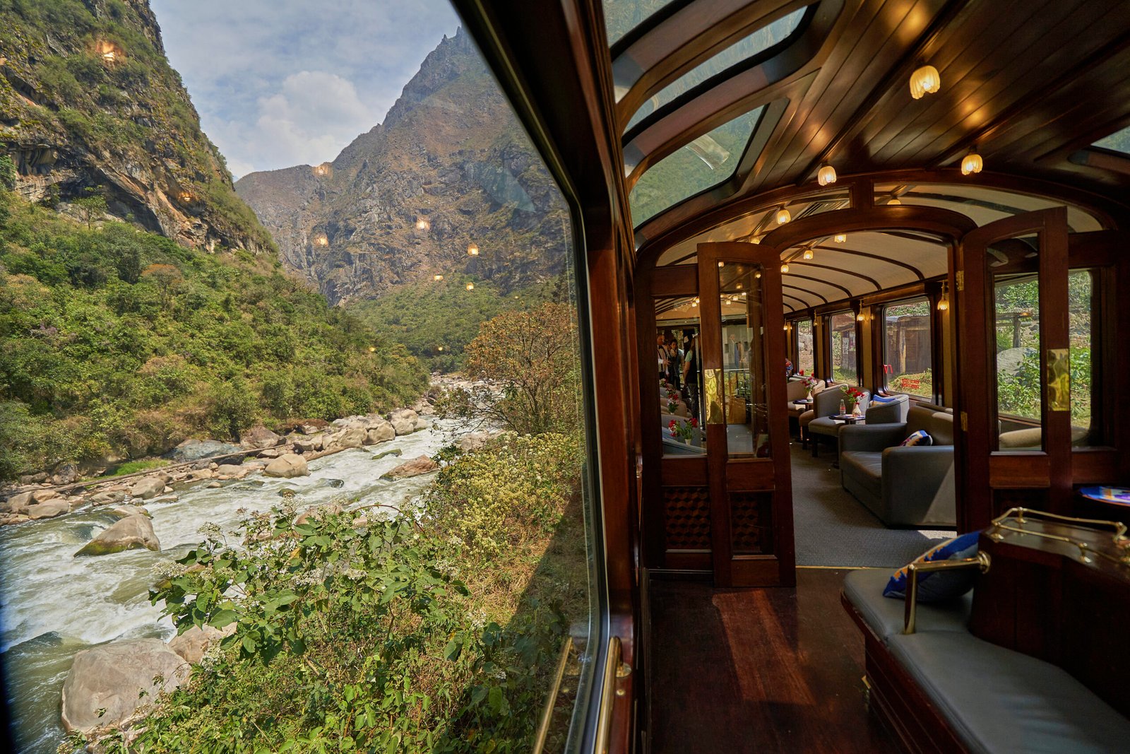 Glass-domed luxury train carriage overlooking a rushing river and steep green mountains, by Alexander Estrada